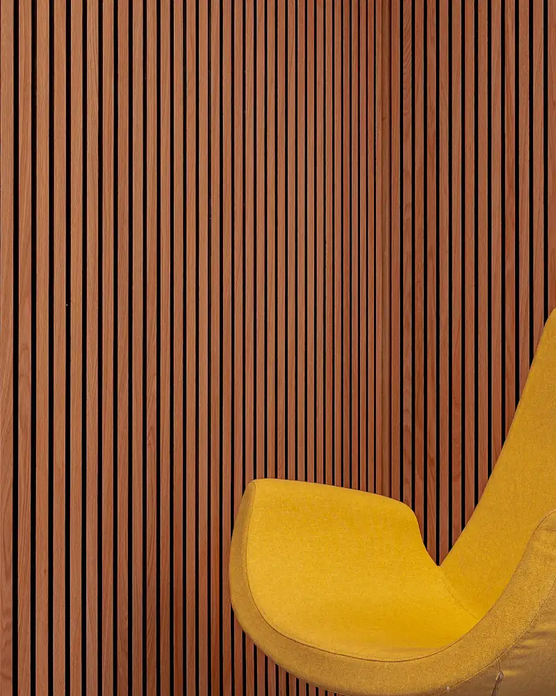 Fluted wooden louver wall behind a yellow chair